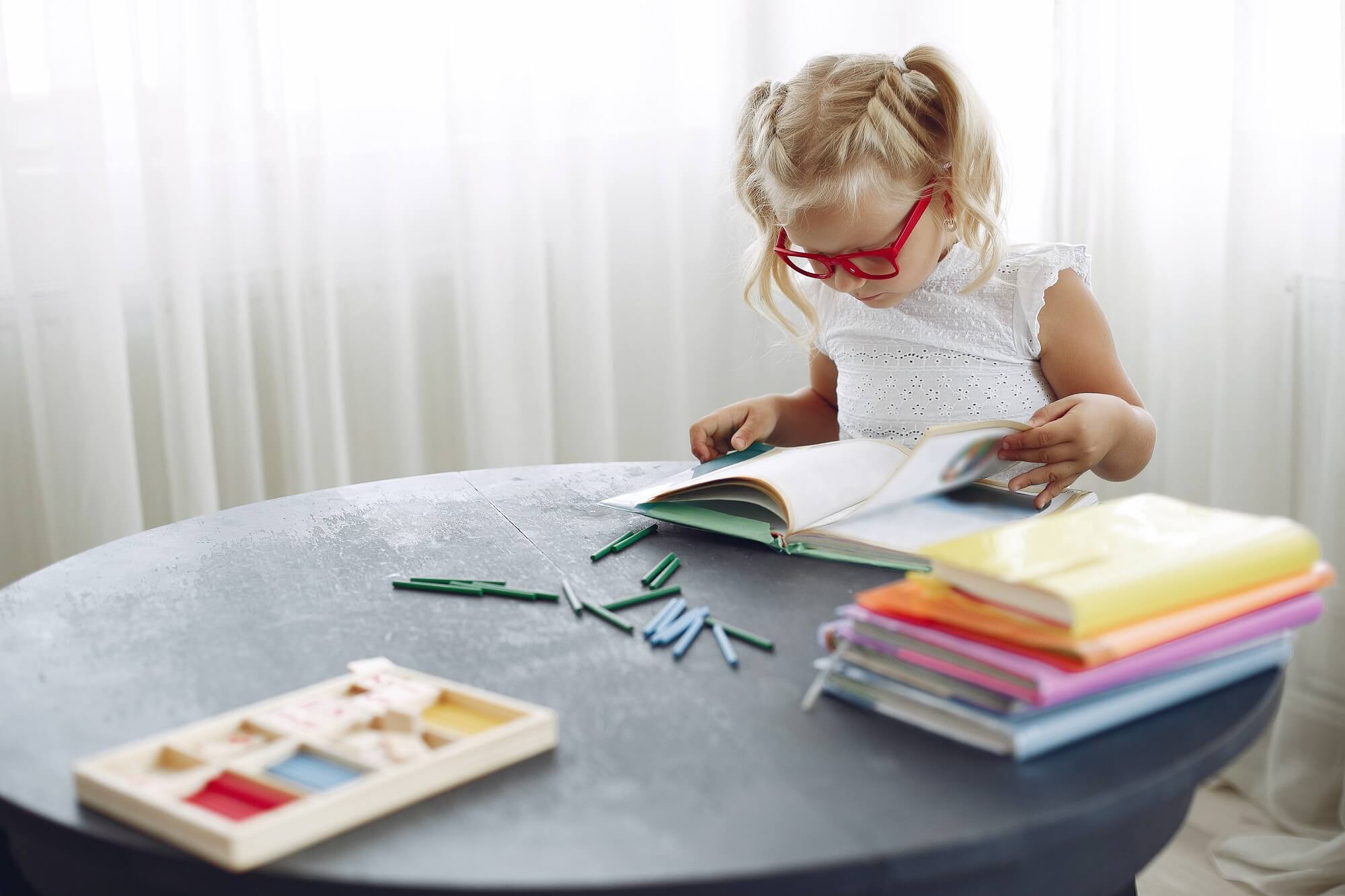 Little girl sitting on a table with books